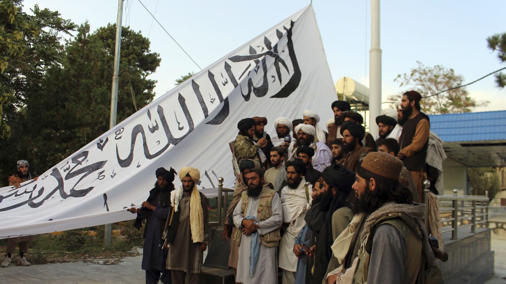 Taliban fighters poses for a photograph while raising their flag Taliban fighters raise their flag at the Ghazni provincial governor's house, in Ghazni, southeastern, Afghanistan, Sunday, Aug. 15, 2021.  - Sputnik International, 1920, 16.08.2021