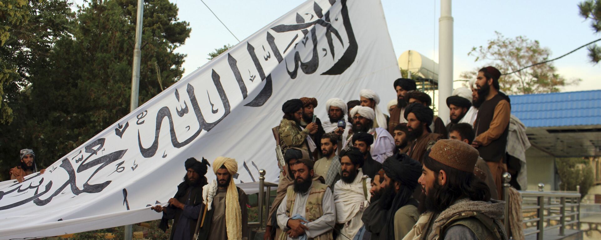 Taliban fighters poses for a photograph while raising their flag Taliban fighters raise their flag at the Ghazni provincial governor's house, in Ghazni, southeastern, Afghanistan, Sunday, Aug. 15, 2021.  - Sputnik International, 1920, 29.08.2021