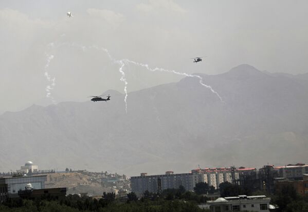 Anti-missile decoy flares are deployed as Black Hawk military helicopters and a dirigible balloon fly over the city of Kabul, Afghanistan, Sunday, 15 August 2021. Taliban fighters entered the outskirts of the Afghan capital on 15 August and said they were awaiting a “peaceful transfer” of the city after promising not to take it by force, but amid the uncertainty panicked workers fled government offices and helicopters landed at the US Embassy. - Sputnik International