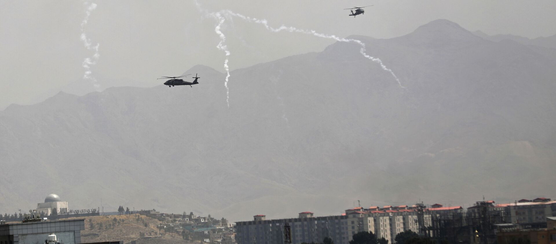 Anti-missile decoy flares are deployed as U.S. Black Hawk military helicopters and a dirigible balloon fly over the city of Kabul, Afghanistan, Sunday, Aug. 15, 2021. - Sputnik International, 1920