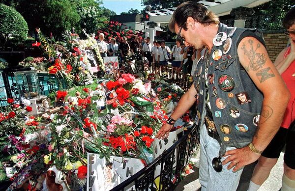 John Dreessen of Maastricht, Holland, looks at flowers and notes left by well-wishers at the grave of legendary rock'n'roll singer Elvis Presley at his Graceland mansion in Memphis. Graceland officials estimate that 30,000 fans visited The King's grave during commemorations for the 20th anniversary of his death at the age of 42. - Sputnik International