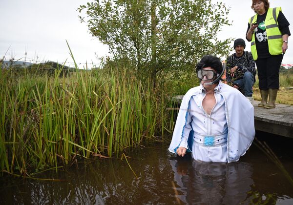 A contestant dressed in an Elvis Presley-themed costume prepares to take part in the 30th World Bog Snorkelling Championships in Waen Rhydd peat bog at Llanwrtyd Wells, South Wales on 30 August 2015. Entrants must negotiate two lengths of a 60-yard trench through the peat bog in the quickest possible time without using any conventional swimming strokes.   - Sputnik International