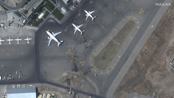 This handout satellite image released by Maxar Technologies shows crowds of people on the tarmac, during the chaotic scene underway at Kabul’s Hamid Karzai International Airport in Afghanistan as thousands of people converged on the tarmac and airport runways as countries attempt to evacuate personnel from the city on August 16, 2021. - Sputnik International