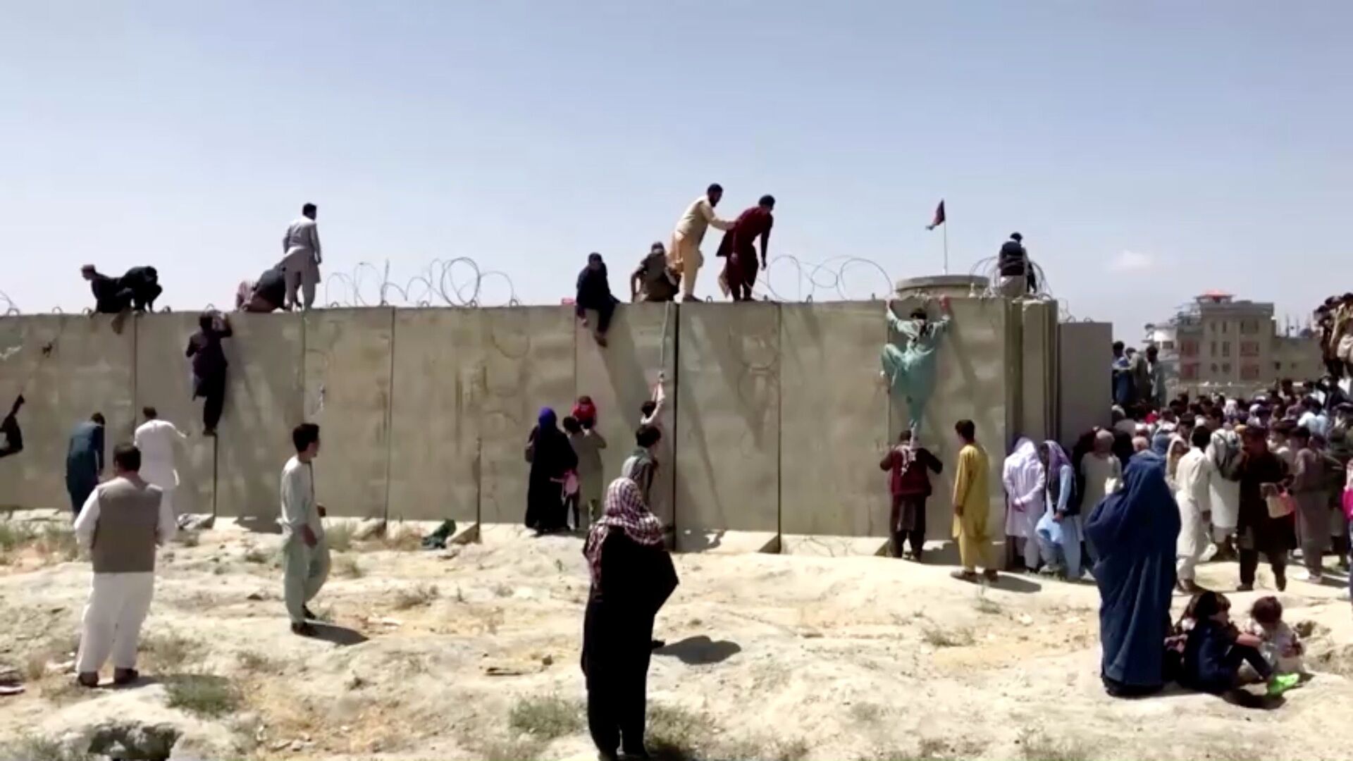 People climb a barbed wire wall to enter the airport in Kabul, Afghanistan August 16, 2021, in this still image taken from a video - Sputnik International, 1920, 07.09.2021