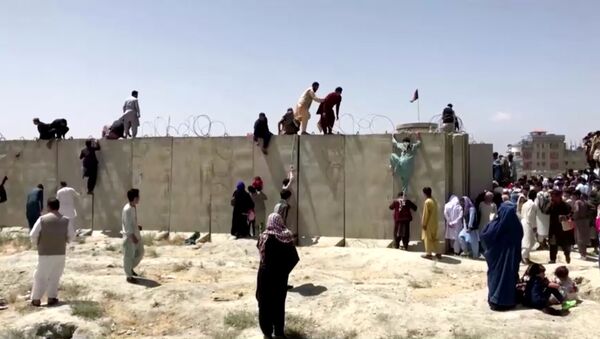 People climb a barbed wire wall to enter the airport in Kabul, Afghanistan August 16, 2021, in this still image taken from a video - Sputnik International