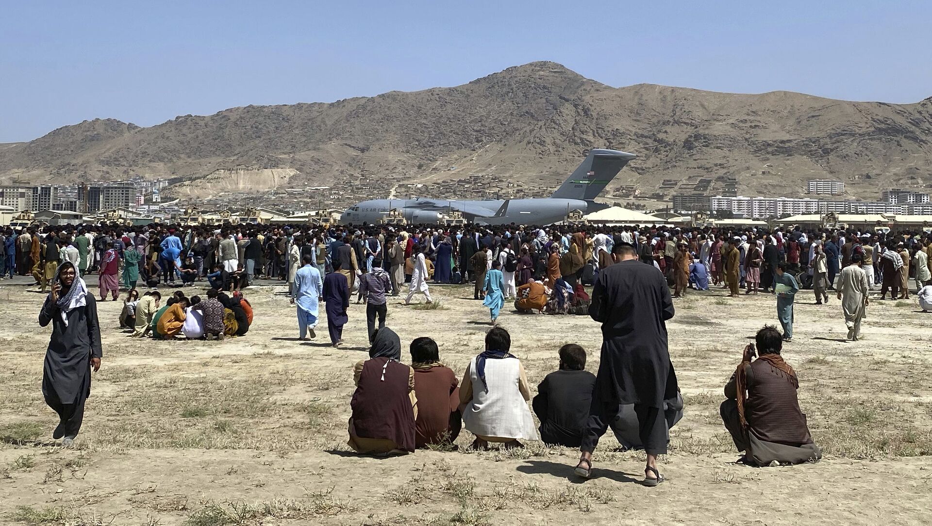 Hundreds of people gather near a U.S. Air Force C-17 transport plane at a perimeter at the international airport in Kabul, Afghanistan, Monday, Aug. 16, 2021 - Sputnik International, 1920, 17.08.2021