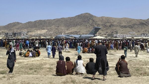 Hundreds of people gather near a U.S. Air Force C-17 transport plane at a perimeter at the international airport in Kabul, Afghanistan, Monday, Aug. 16, 2021. On Monday, the U.S. military and officials focus was on Kabul’s airport, where thousands of Afghans trapped by the sudden Taliban takeover rushed the tarmac and clung to U.S. military planes deployed to fly out staffers of the U.S. Embassy, which shut down Sunday, and others - Sputnik International
