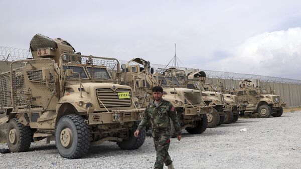 An Afghan army soldier walks past Mine Resistant Ambush Protected vehicles, MRAP, that were left after the American military left Bagram air base, in Parwan province north of Kabul, Afghanistan, Monday, July 5, 2021. - Sputnik International
