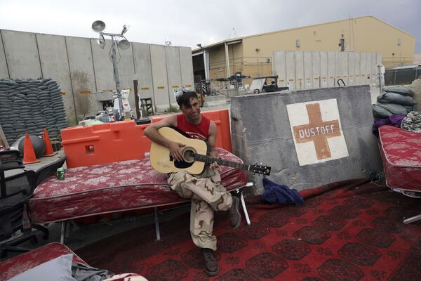 In this 5 July 2021 file photo, an Afghan soldier plays a guitar that was left behind after the American military departed Bagram air base, in Parwan province north of Kabul, Afghanistan. - Sputnik International