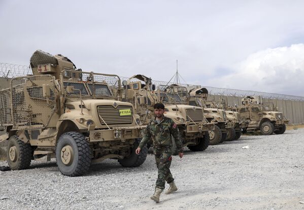 An Afghan army soldier walks past Mine Resistant Ambush Protected vehicles, MRAPs, that were left after the American military left Bagram air base, in Parwan province north of Kabul, Afghanistan, Monday, 5 July 2021.  - Sputnik International