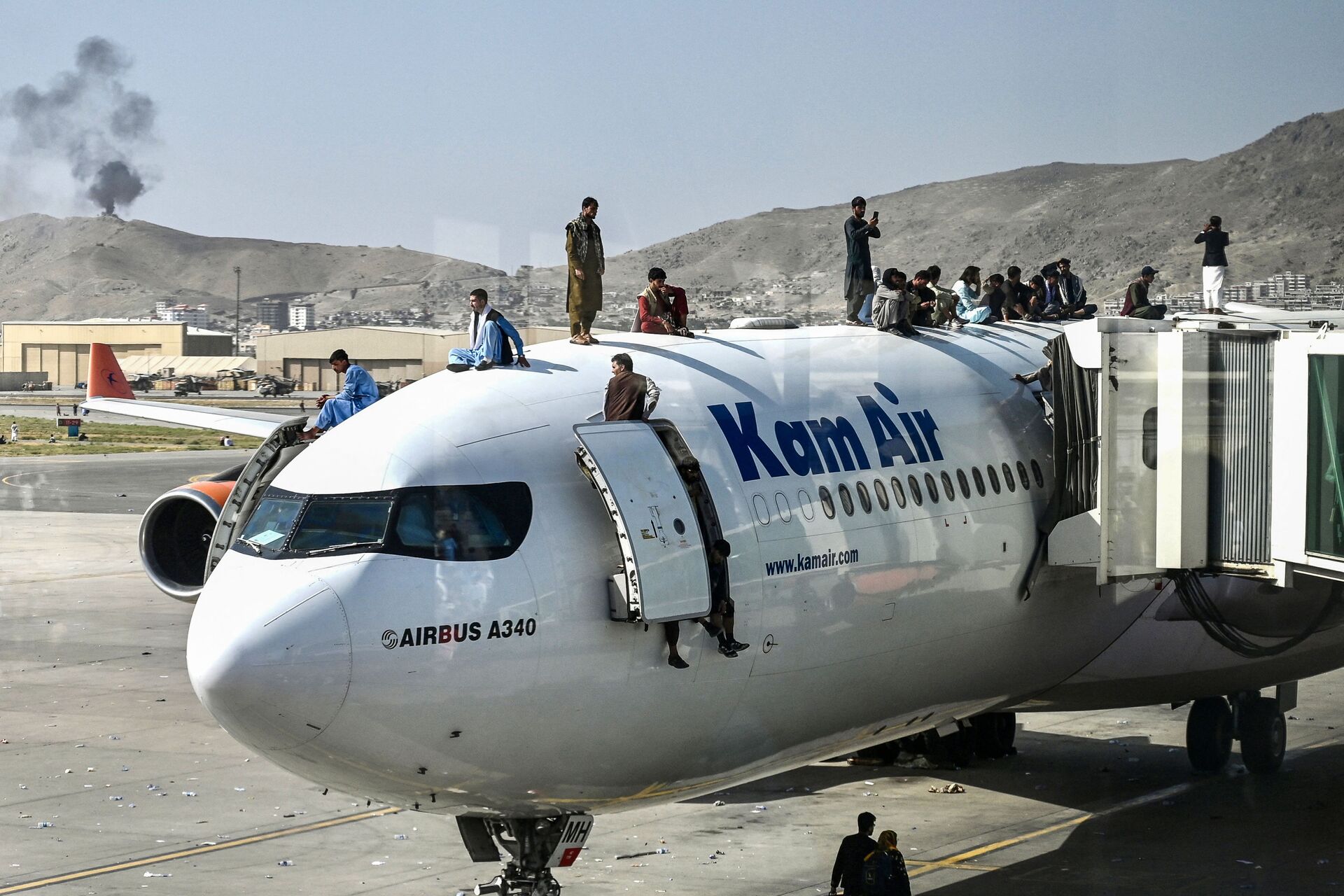Afghan people climb atop a plane as they wait at the airport in Kabul on August 16, 2021, after a stunningly swift end to Afghanistan's 20-year war, as thousands of people mobbed the city's airport trying to flee the group's feared hardline brand of Islamist rule - Sputnik International, 1920, 07.09.2021