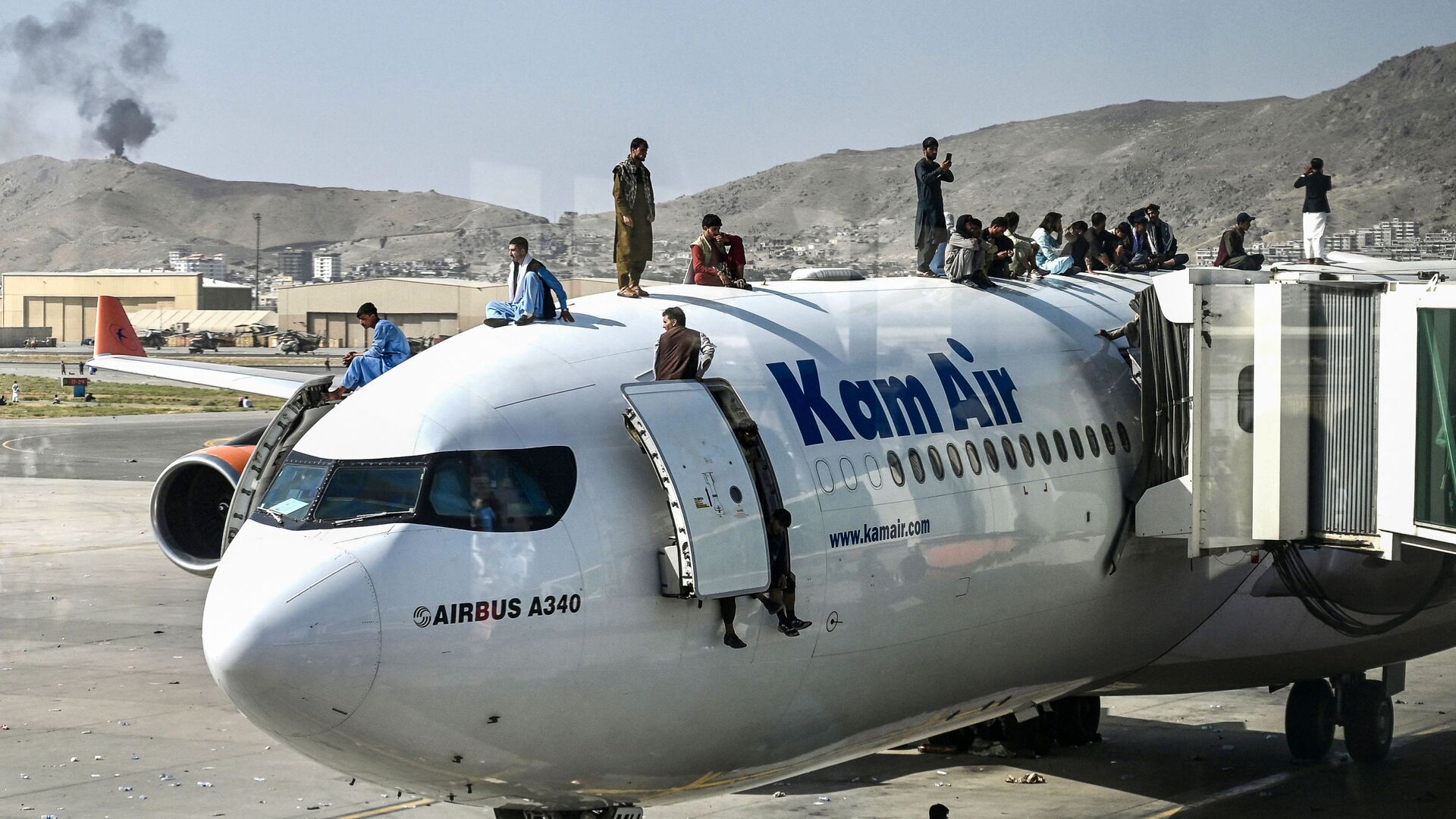 Afghan people climb atop a plane as they wait at the airport in Kabul on August 16, 2021, after a stunningly swift end to Afghanistan's 20-year war, as thousands of people mobbed the city's airport trying to flee the group's feared hardline brand of Islamist rule - Sputnik International, 1920, 19.08.2021