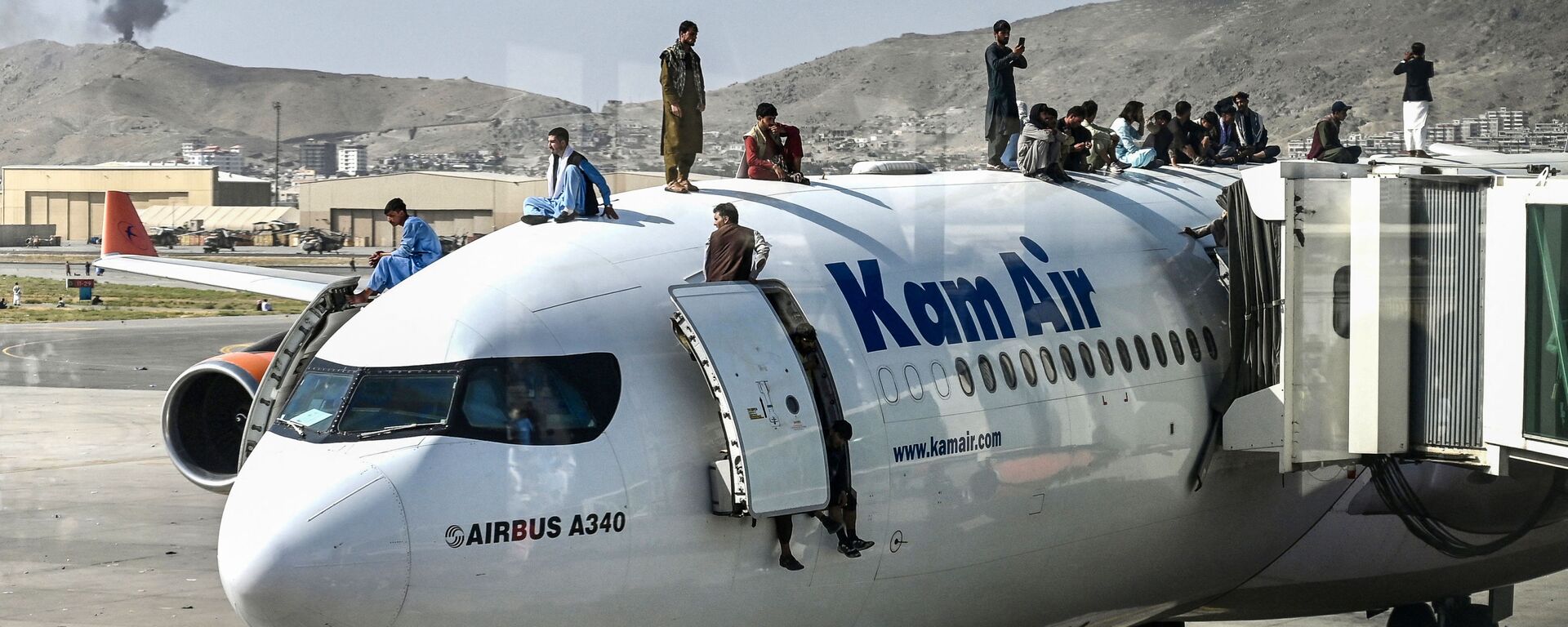 Afghan people climb atop a plane as they wait at the airport in Kabul on August 16, 2021, after a stunningly swift end to Afghanistan's 20-year war, as thousands of people mobbed the city's airport trying to flee the group's feared hardline brand of Islamist rule - Sputnik International, 1920
