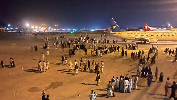 An undated amateur picture obtained by Reuters on August 19, 2021 shows people walking on the tarmac of the airport in Kabul, Afghanistan. - Sputnik International