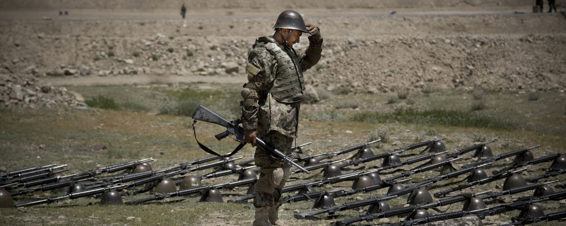 An Afghan Army soldier pauses before dropping his helmet and his gun next to his comrade's equipment at a training facility in the outskirts of Kabul, Afghanistan on Wednesday, May 8, 2013. - Sputnik International, 1920, 20.08.2021