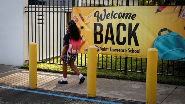A student wearing a protective masks, walks past a “Welcome back” banner on the first day of school, amid the coronavirus disease (COVID-19) pandemic, at St. Lawrence Catholic School in North Miami Beach, Florida, U.S. August 18, 2021. - Sputnik International