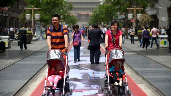 A couple pushes their young children in prams along a street in Beijing on May 19, 2013 - Sputnik International