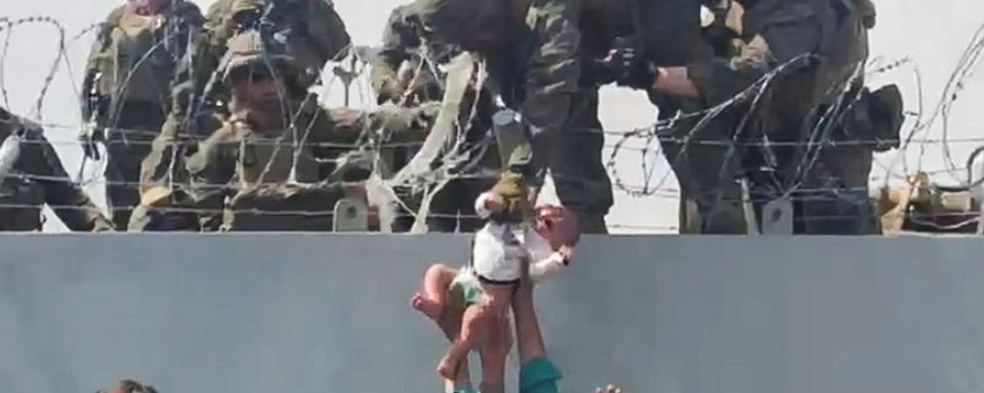 A baby is handed over to the American army over the perimeter wall of the airport for it to be evacuated, in Kabul, Afghanistan, August 19, 2021, in this still image taken from video obtained from social media. - Sputnik International, 1920, 15.09.2021