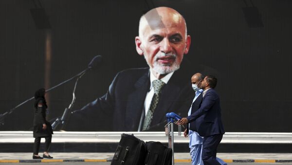 Passengers walk to the departures terminal of Hamid Karzai International Airport in Kabul, Afghanistan, on Saturday, Aug. 14, 2021, past a mural of President Ashraf Ghani, as the Taliban offensive encircled the capital. - Sputnik International