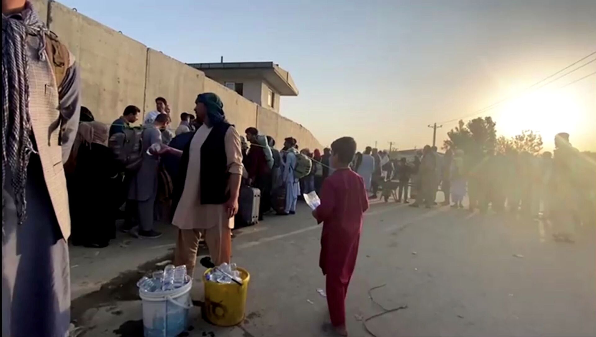 A man instructs people to queue as they stand with their belongings outside Kabul airport, Afghanistan, August 22, 2021 in this still image taken from video - Sputnik International, 1920, 23.08.2021