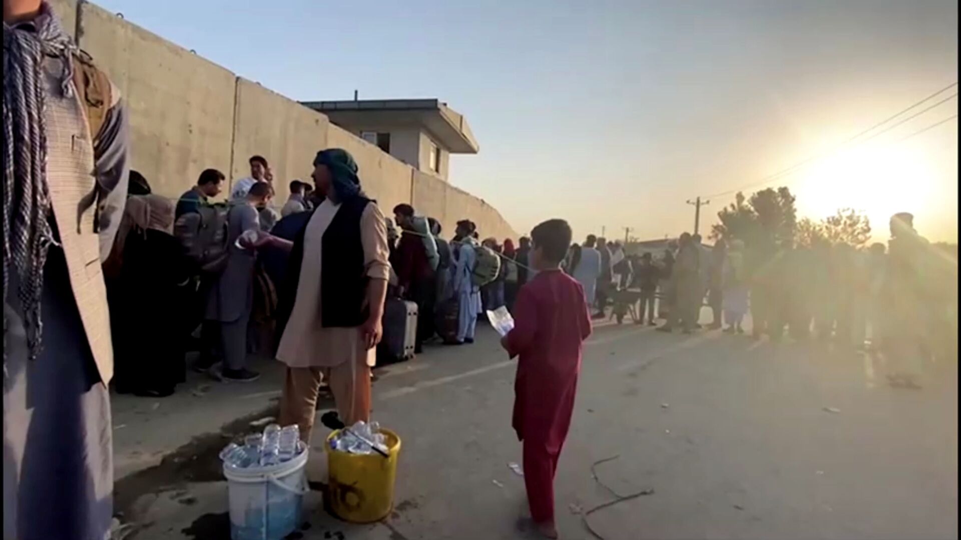 A man instructs people to queue as they stand with their belongings outside Kabul airport, Afghanistan, August 22, 2021 in this still image taken from video - Sputnik International, 1920, 07.09.2021
