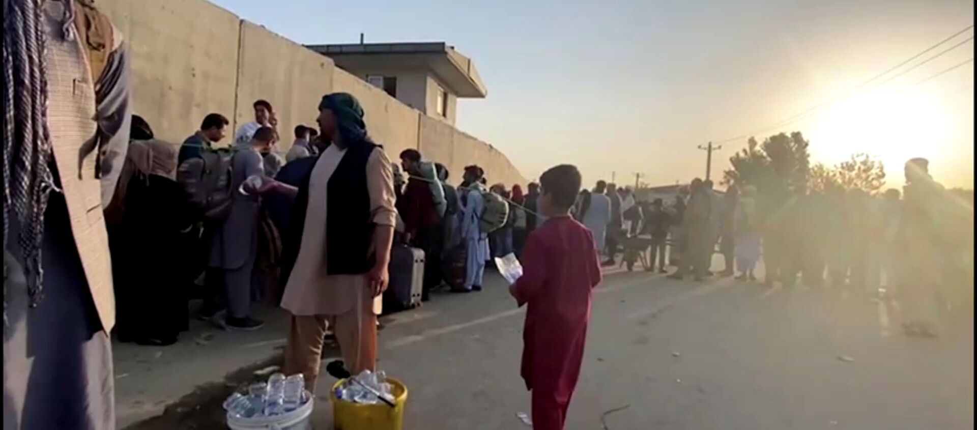 A man instructs people to queue as they stand with their belongings outside Kabul airport, Afghanistan, August 22, 2021 in this still image taken from video - Sputnik International, 1920, 23.08.2021