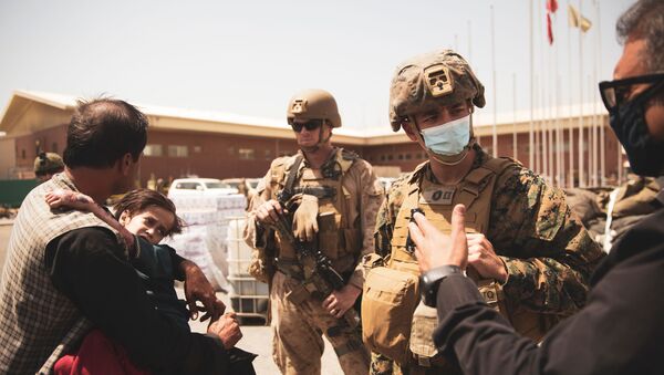 A U.S. Navy medical surgeon with the 24th Marine Expeditionary Unit (MEU) talks to an interpreter as he provides medical assistance to a family during an evacuation at Hamid Karzai International Airport, Kabul, Afghanistan, August 21, 2021. Picture taken August 21, 2021 - Sputnik International
