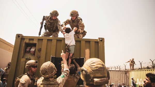 UK coalition forces, Turkish coalition forces, and U.S. Marines assist a child during an evacuation at Hamid Karzai International Airport, Kabul, Afghanistan, in this photo taken on August 20, 2021 - Sputnik International