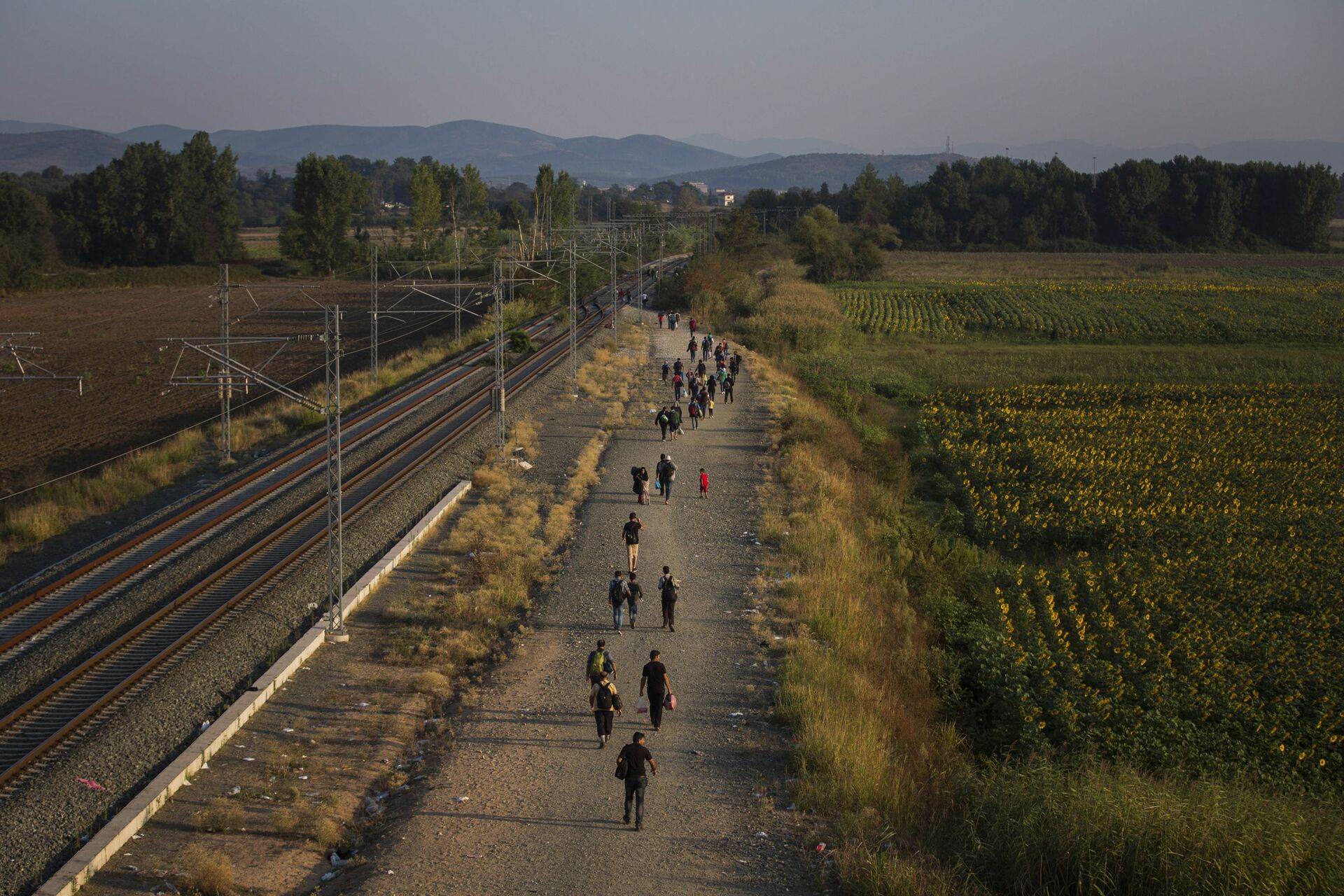 FILE - In this Thursday Aug. 27, 2015 file photo, migrants walk alongside railway tracks at Idomeni, northern Greece to cross the border and enter Macedonia. In the 28-nation EU, some countries have sought to block the unprecedented flow of migrants fleeing war or poverty in the Middle East and Africa. (AP Photo/Santi Palacios, File) - Sputnik International, 1920, 07.09.2021
