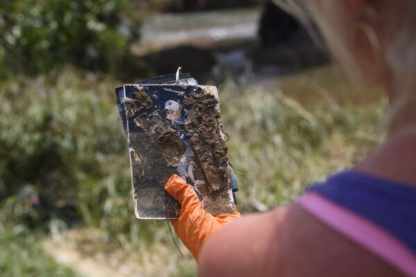 A woman holds a photo she found as she searches for personal items lost in recent flooding, Monday, 23 August 2021, in Waverly, Tennessee. Although she did not recognise the person in the photo, she planned on posting it on social media to reconnect it with the owner. - Sputnik International