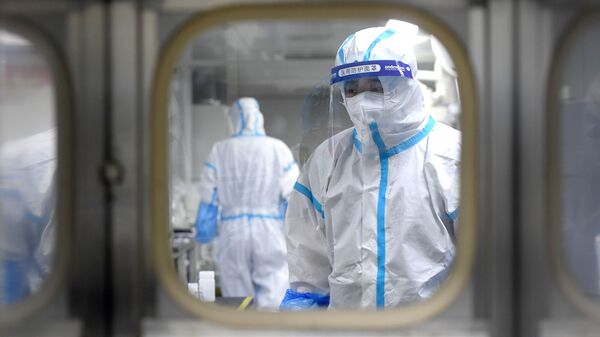 Medical workers in protective suits test nucleic acid samples inside a Huo-Yan (Fire Eye) laboratory of BGI, following new cases of the coronavirus disease (COVID-19) in Wuhan, Hubei province, China early August 5, 2021 - Sputnik International