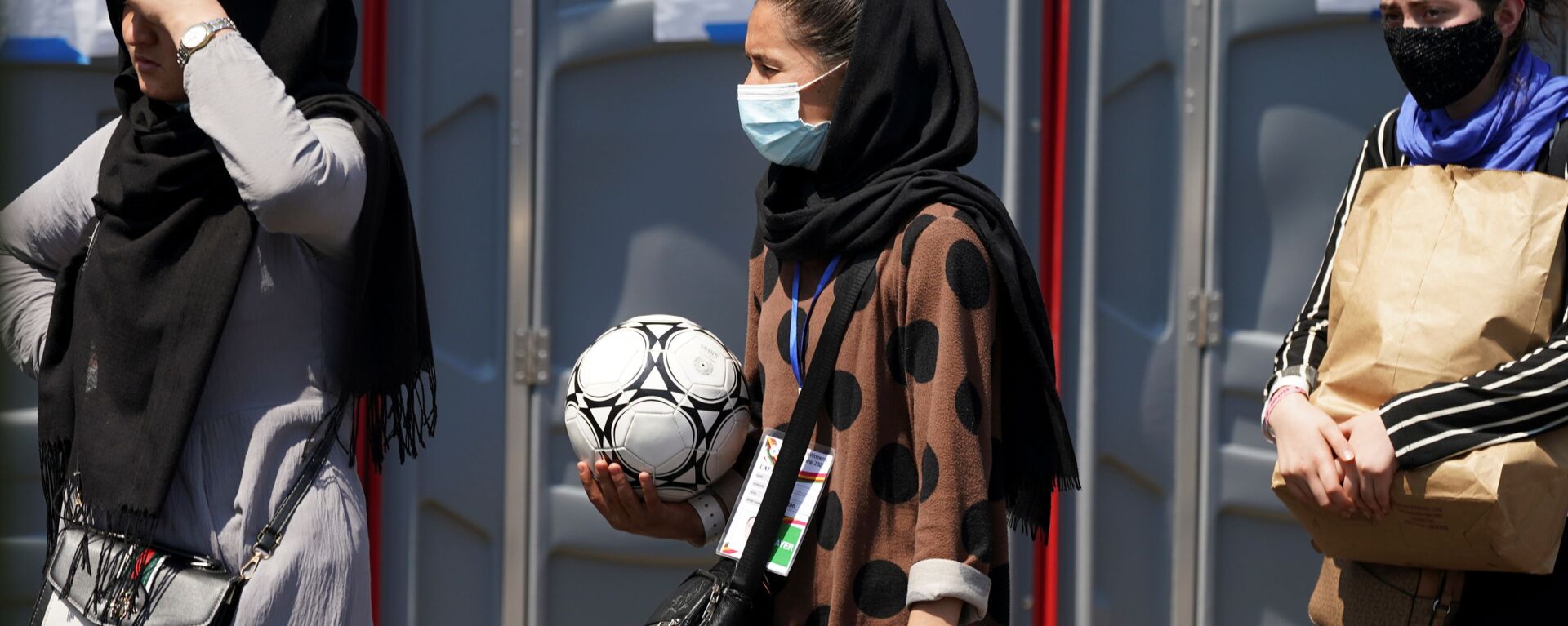 An Afghan woman holding a soccer ball and wearing a CAFA (Central Asian Football Association) credential, waits in line at a processing center for refugees evacuated from Afghanistan at the Dulles Expo Center near Dulles International Airport in Chantilly, Virginia, U.S., August 24, 2021 - Sputnik International, 1920, 20.09.2021