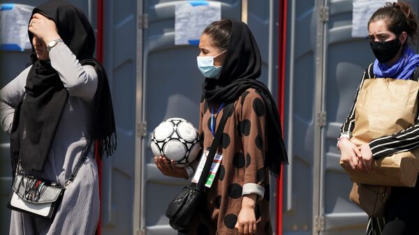An Afghan woman holding a soccer ball and wearing a CAFA (Central Asian Football Association) credential, waits in line at a processing center for refugees evacuated from Afghanistan at the Dulles Expo Center near Dulles International Airport in Chantilly, Virginia, U.S., August 24, 2021 - Sputnik International