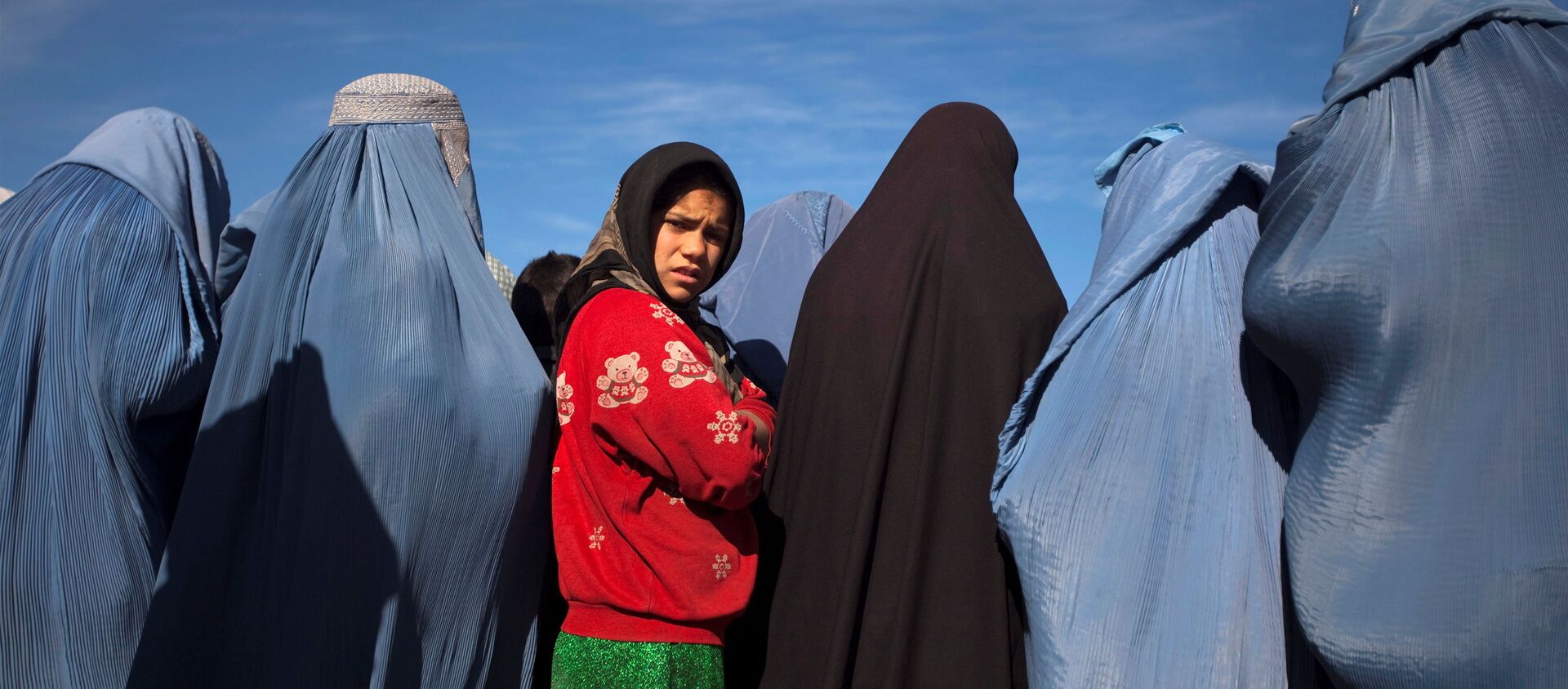 An Afghan girl stands among widows clad in burqas during a cash for work project by humanitarian organisation CARE International in Kabul, Afghanistan January 6, 2010 - Sputnik International, 1920, 03.09.2021