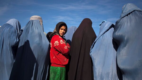 An Afghan girl stands among widows clad in burqas during a cash for work project by humanitarian organisation CARE International in Kabul, Afghanistan January 6, 2010 - Sputnik International