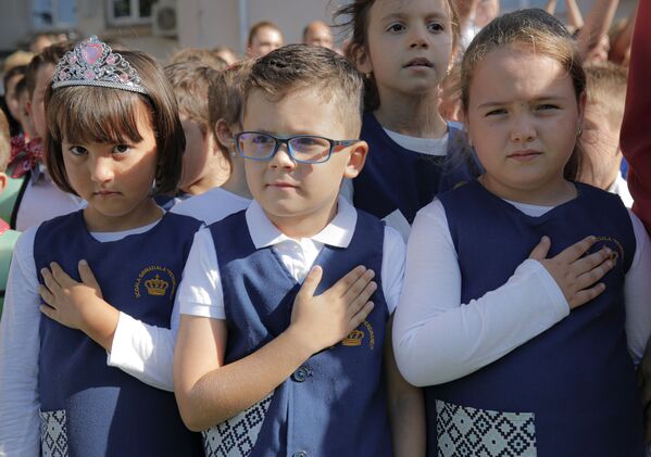 Children hold their hands on their chests as the national anthem is played during festivities marking the beginning of the school year at the Ferdinand I school in Bucharest, Romania. - Sputnik International
