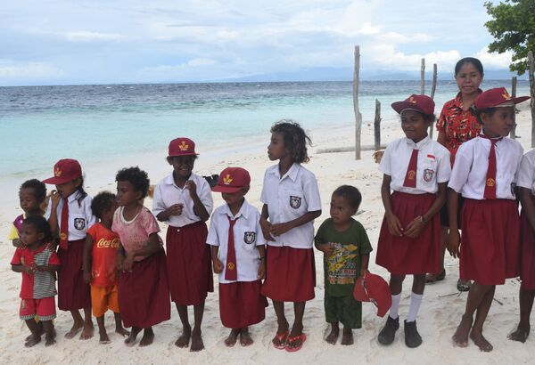 Byak Betew tribal children in their school uniforms as they line up to welcome visitors to the island of Saukabu, one of the 1,500 islands of Raja Ampat, Indonesia. Raja Ampat – which means Four Kings – is made up of 1,500 islands and has one of the most biodiverse marine habitats on Earth. But its education and health system lags far behind other parts of Southeast Asia's largest economy. Many students do not finish high school, instead they take care of siblings and spending time on the palm-fringed beaches. - Sputnik International