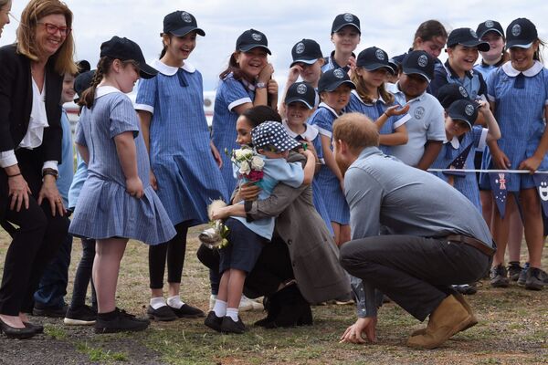 Britain's Prince Harry (R) looks on as his wife Meghan, the Duchess of Sussex, is hugged by student Luke Vincent of Buninyong Public School following the couple's arrival at Dubbo Regional Airport in Dubbo on 17 October 2018. - Sputnik International