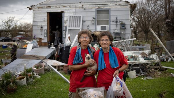 Twin sisters Bridget and Rosalie Serigny, 66, hold their cat Frost as they pose for a photograph after returning to their damaged home in the aftermath of Hurricane Ida in Golden Meadow, Louisiana, U.S., September 1, 2021. - Sputnik International