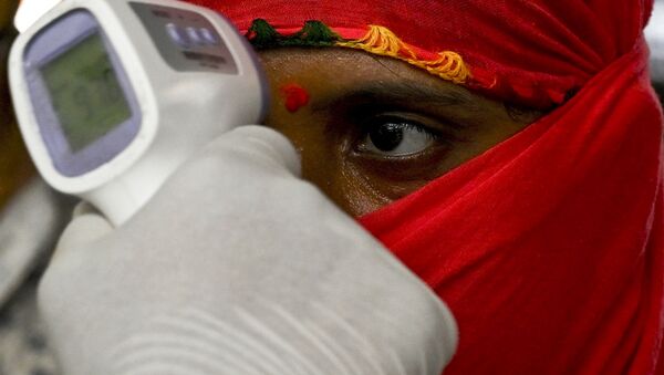 A health worker takes the body temperature of incoming passengers at a railway terminus following restrictions imposed by the state government amidst rising Covid-19 coronavirus cases Mumbai on April 7, 2021 - Sputnik International