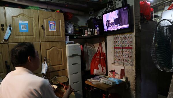 A resident watches a television screen showing news broadcasting astronauts of the Shenzhou-12 mission conducting extravehicular activities outside the core module Tianhe of the Chinese space station, at his home in Beijing, China August 20, 2021.  - Sputnik International