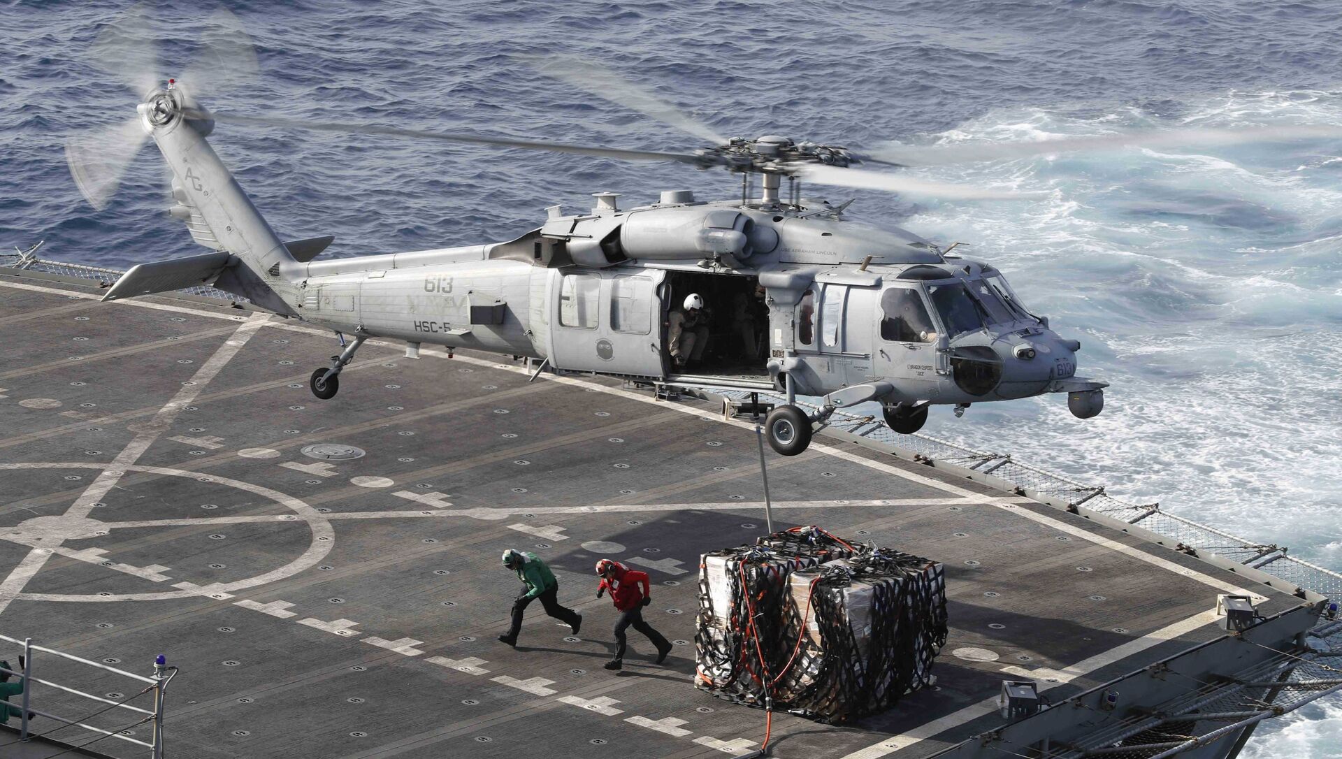 This handout picture released by the US Navy on May 19, 2019 shows a MH-60S Sea Hawk helicopter from the Nightdippers of Helicopter Sea Combat Squadron (HSC) 5 transporting cargo from the fast combat support ship USNS Arctic (T-AOE 8) to the Nimitz-class aircraft carrier USS Abraham Lincoln (CVN 72) during a replenishment-at-sea.  - Sputnik International, 1920, 04.09.2021