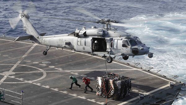 This handout picture released by the US Navy on May 19, 2019 shows a MH-60S Sea Hawk helicopter from the Nightdippers of Helicopter Sea Combat Squadron (HSC) 5 transporting cargo from the fast combat support ship USNS Arctic (T-AOE 8) to the Nimitz-class aircraft carrier USS Abraham Lincoln (CVN 72) during a replenishment-at-sea.  - Sputnik International