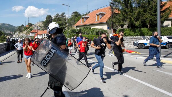Demonstrators run away as a police member stands guard during a protest against enthronement of Bishop Joanikije in Cetinje, Montenegro - Sputnik International