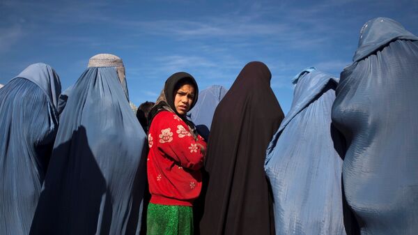 An Afghan girl stands among widows clad in burqas during a cash for work project by humanitarian organisation CARE International in Kabul - Sputnik International