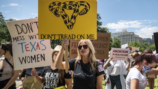 Protesters hold up signs at a protest outside the Texas state capitol on May 29, 2021 in Austin, Texas. - Sputnik International