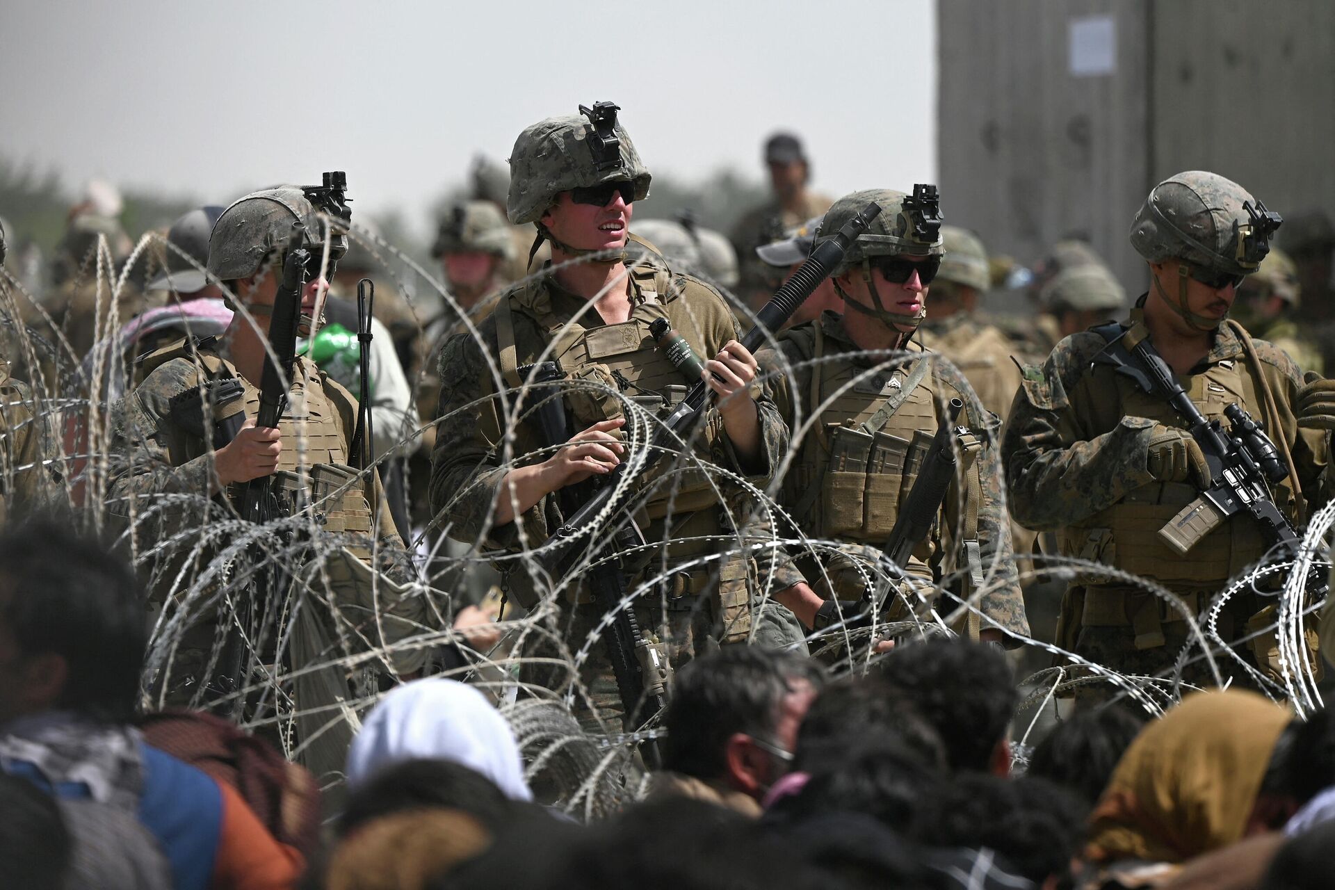 US soldiers stand guard behind barbed wire as Afghans sit on a roadside near the military part of the airport in Kabul on August 20, 2021, hoping to flee from the country after the Taliban's military takeover of Afghanistan - Sputnik International, 1920, 07.09.2021