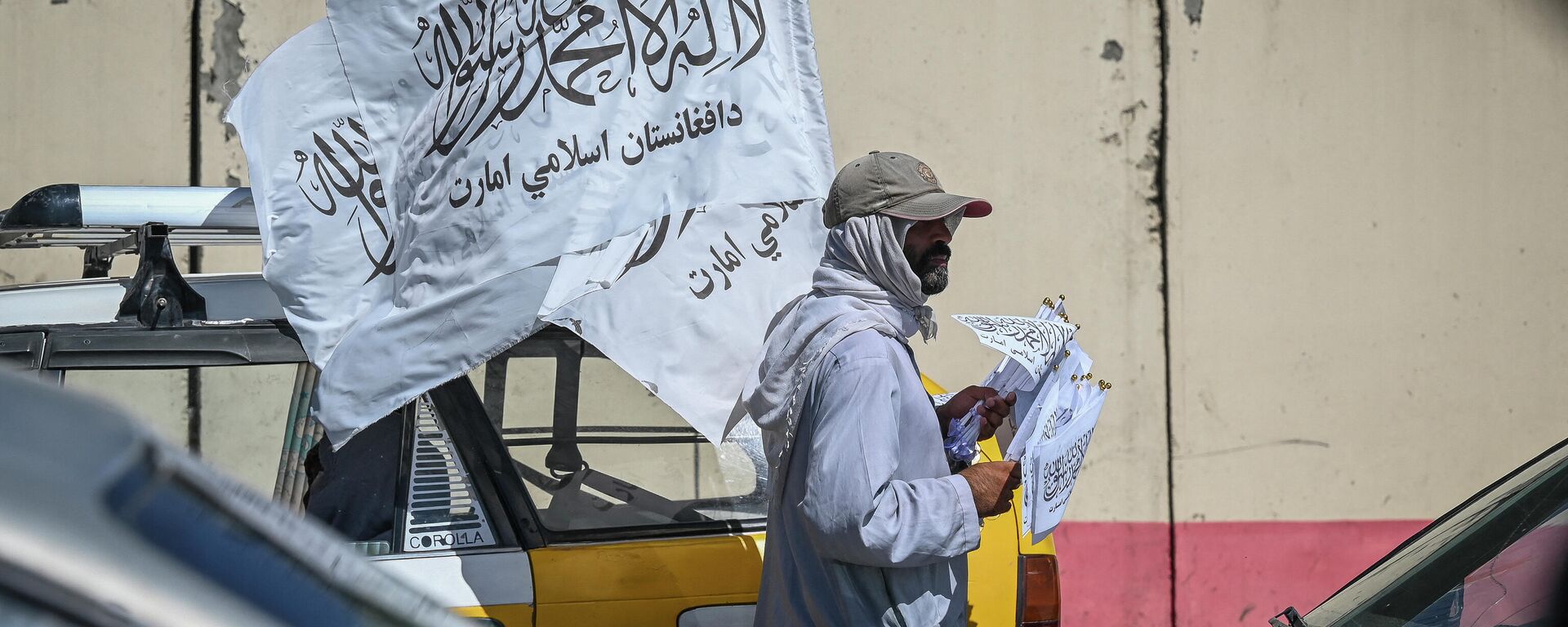 A mobile hawker carries Taliban flags as commuters make their way along a road in Kabul on September 5, 2021. - Sputnik International, 1920, 07.09.2021