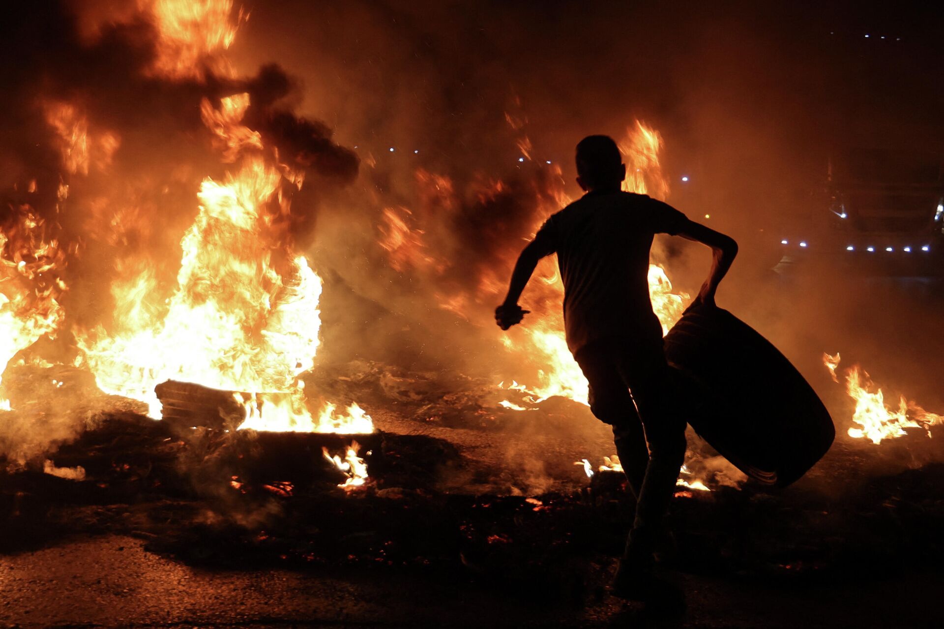 A Palestinian youth carries a tyre before setting it ablaze, during confrontations with Israeli security forces following a rally in support of Palestinian prisoners held in Israeli jails, at the Hawara checkpoint near the West Bank town of Nablus, on September 8, 2021. - Sputnik International, 1920, 23.06.2022