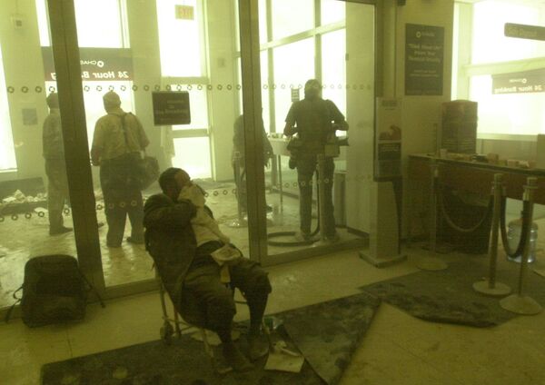 An injured man waits for help as others take refuge in a bank near the World Trade Center towers on 11 September 2001, in New York. - Sputnik International
